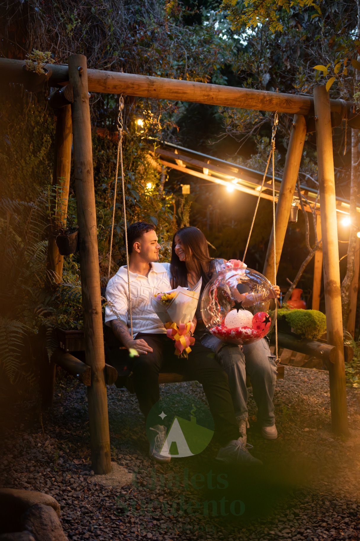 Pareja en columpio de madera con luces cálidas en la noche