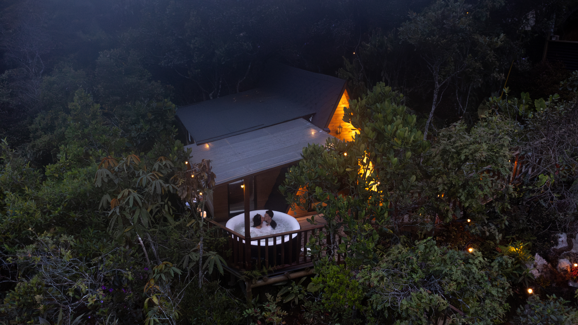 Pareja en jacuzzi privado del chalet rodeado de bosque en la noche